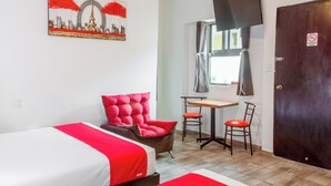 Une chambre d’hôtel avec deux lits, une chaise rouge, une petite table et un téléviseur.