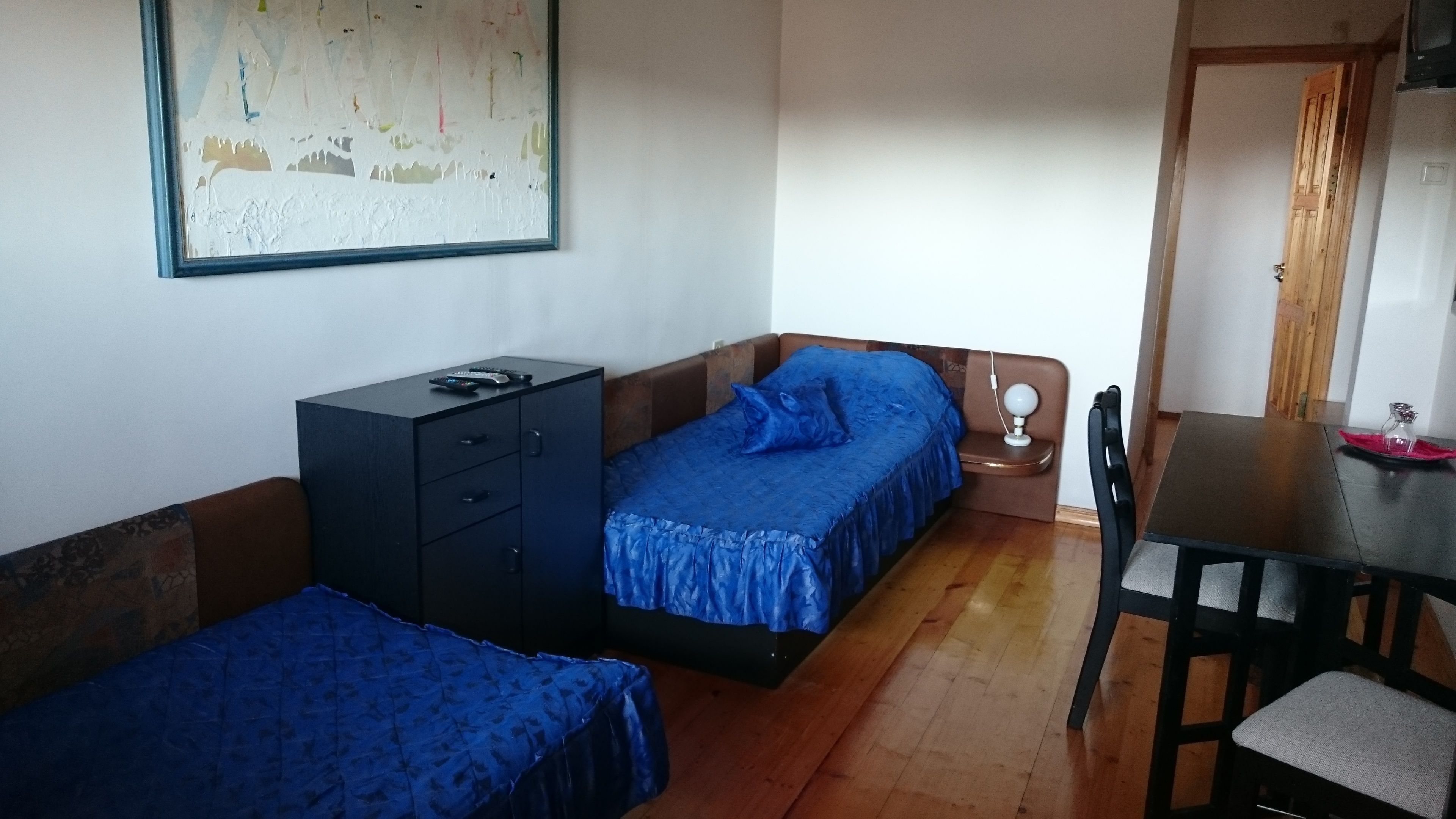 A small, cozy room with two single beds, a desk, a chair, and a cabinet.