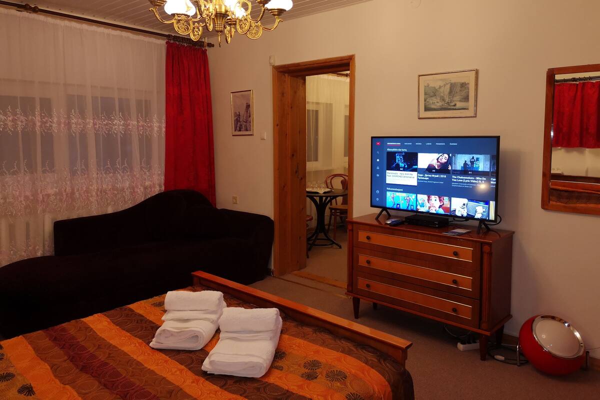 A hotel room with a bed, a TV, a dresser, and a red speaker.