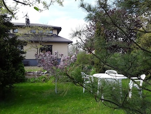 A house with a tiled roof, surrounded by lush greenery and flowering plants.