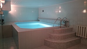 A rectangular hot tub with steps leading into it, surrounded by white tiled walls. - Rural tourism homestead JOLE (Rumšiškes)