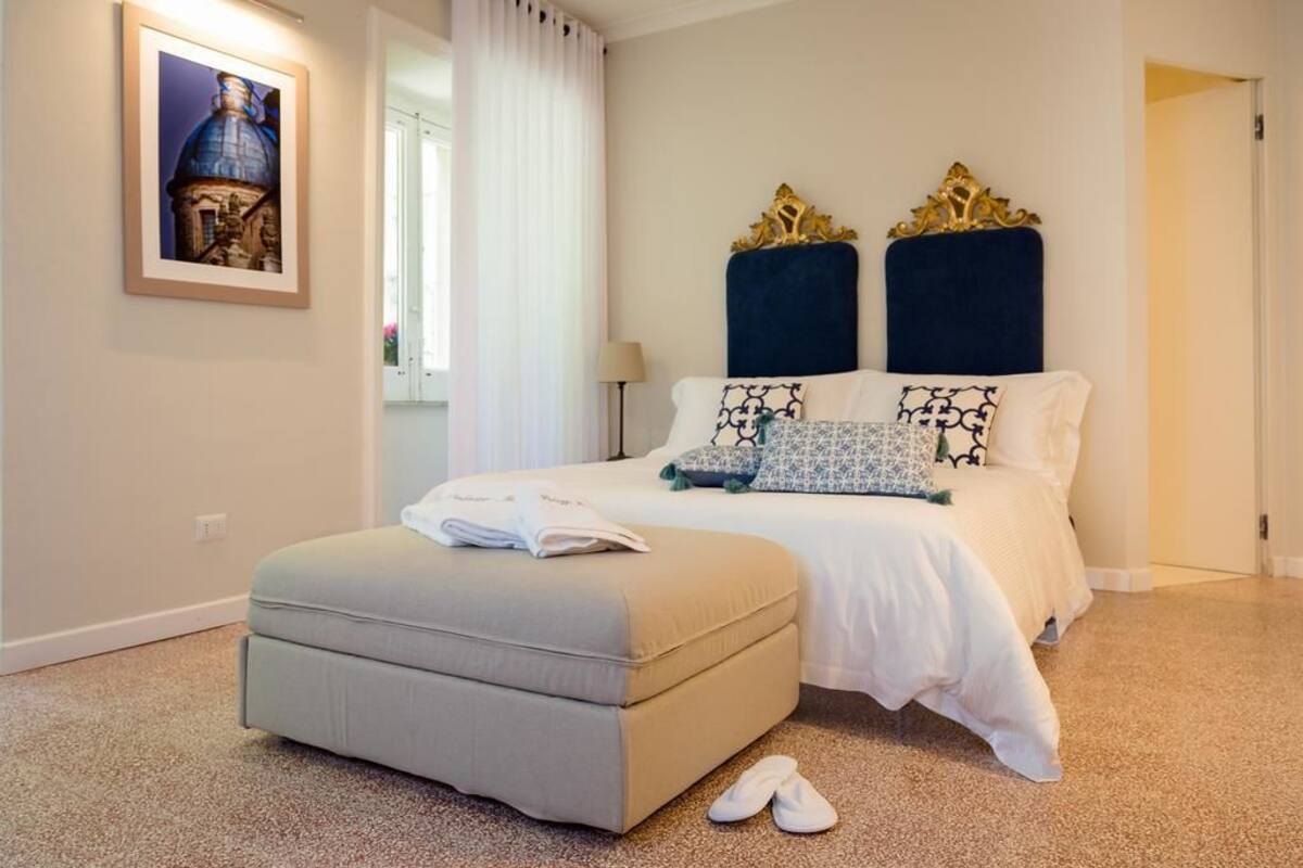 A bedroom with a bed, a bedside table, a lamp, and a framed picture on the wall.
