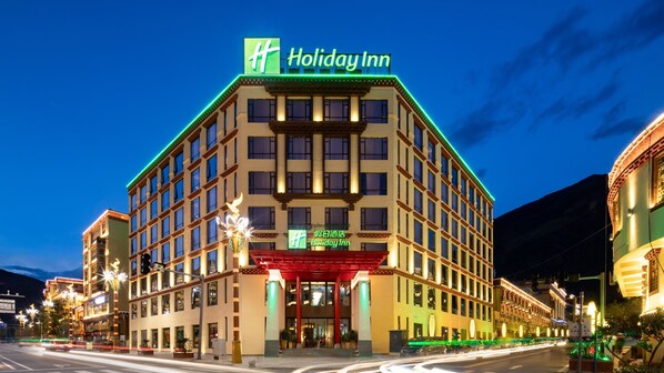 A Holiday Inn hotel with a prominent sign, large windows, and a well-lit entrance.