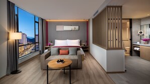 Et moderne hotelværelse med et stort vindue, en sofa, et lille bord og et badeværelse med et spejl og en vask.
