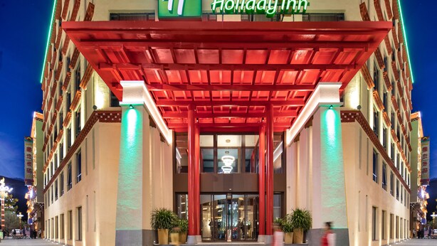 A Holiday Inn hotel with a red canopy entrance, large windows, and a sign in both English and Chinese. - Holiday Inn Batang by IHG (Garze)