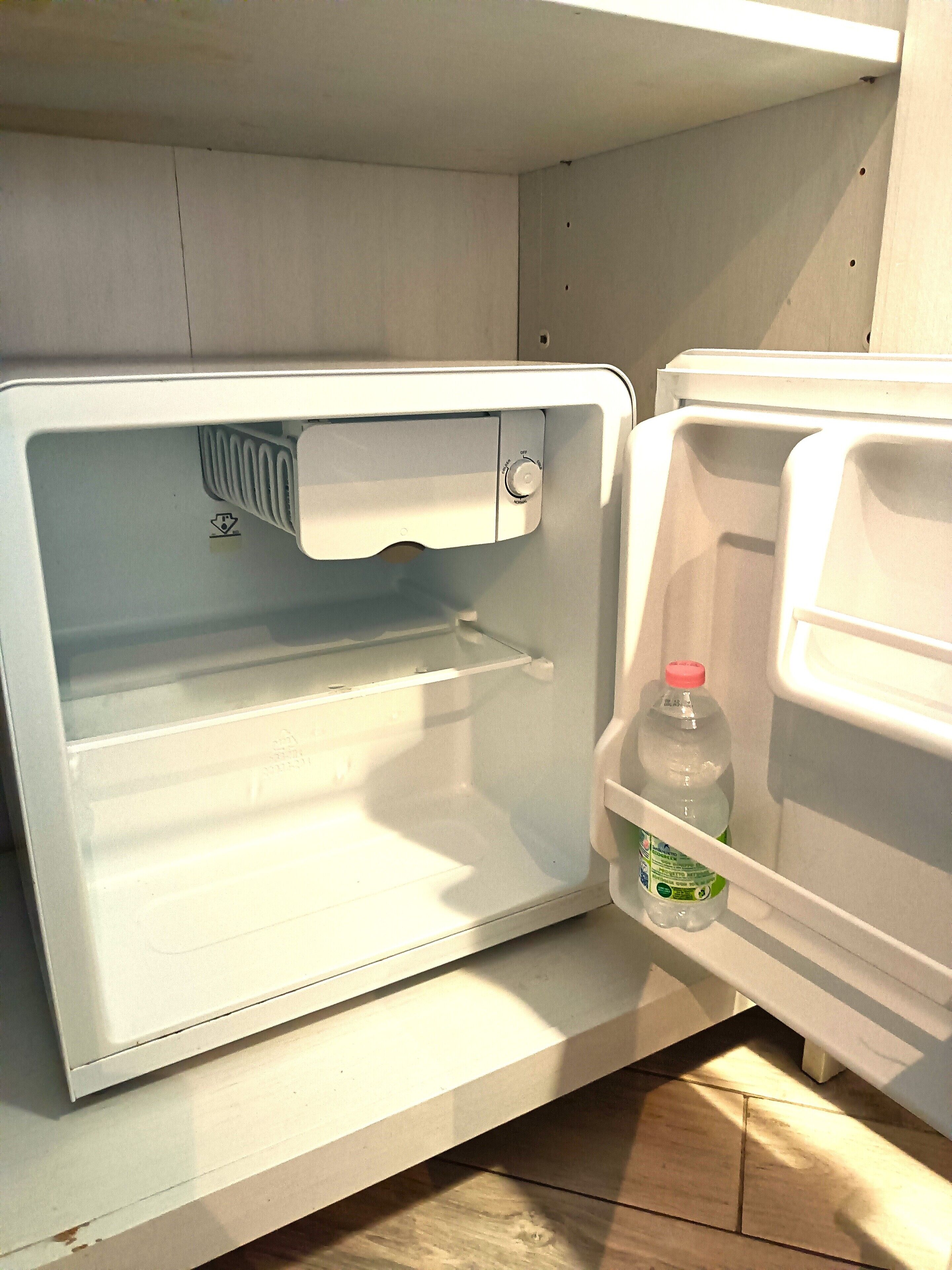 An open refrigerator with a bottle of water and a carton of juice on the door shelf.