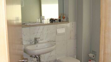 A bathroom with a sink, toilet, and mirror.