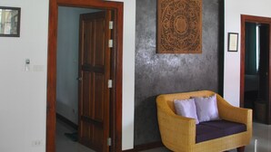 Een ruime kamer met een grote houten deur, een geweven bank en een decoratief kunstwerk aan de muur.