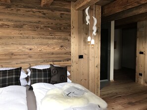 A wooden cabin-style room with a bed, pillows, and a white furry rug.