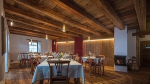 A dining area with wooden beams, tables set for a meal, and hanging pendant lights. - Grizzly Haus (Ville di Fiemme)