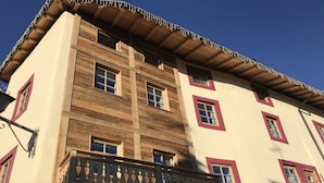 A multi-story building with a wooden facade and red-framed windows. - Grizzly Haus (Ville di Fiemme)