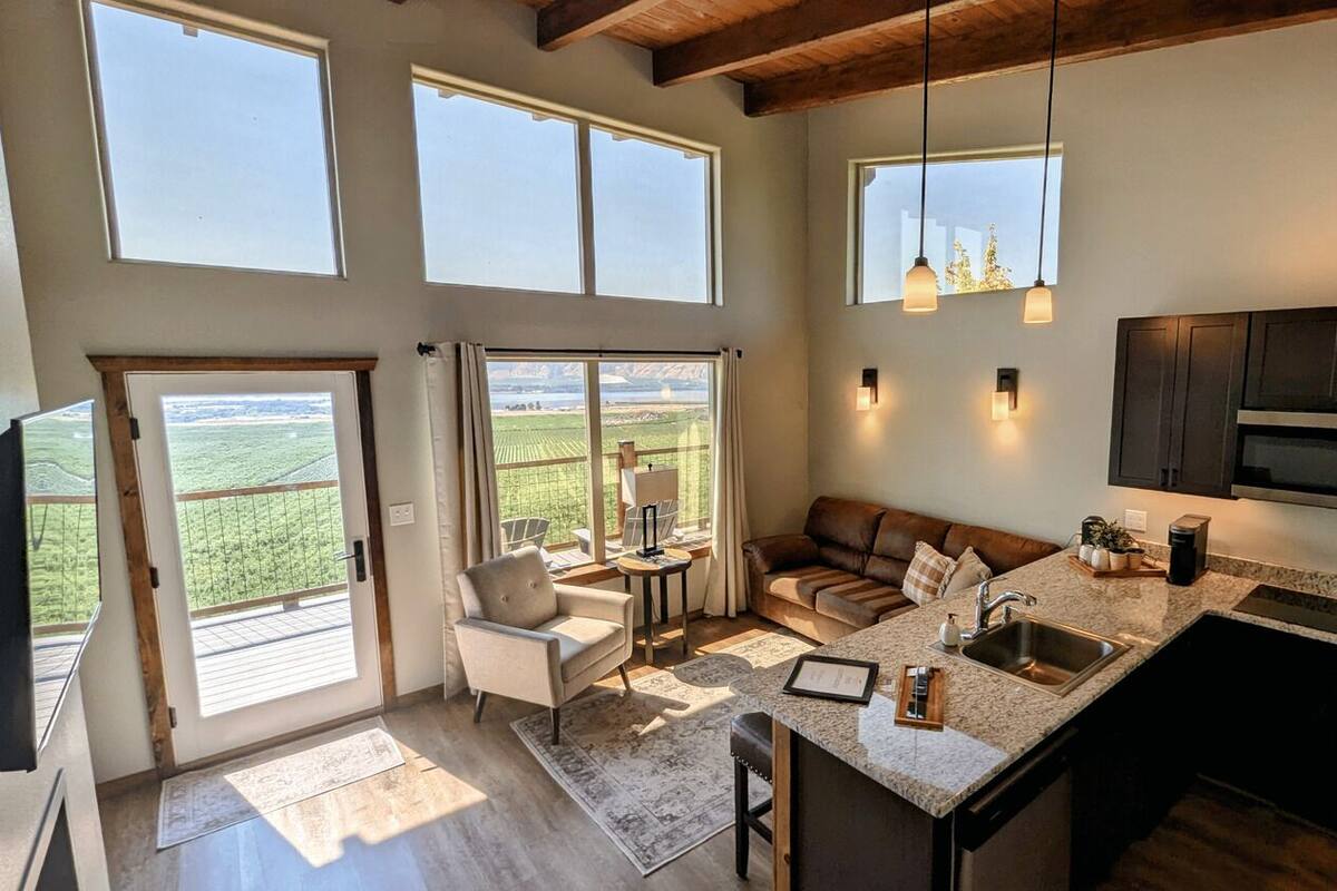 A spacious living area with a large window, a cozy seating area, and a kitchen with modern appliances.