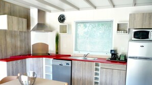 A modern kitchen with a red countertop, stainless steel appliances, and wooden cabinetry. - 4/6-person CLIMATIZED WOODEN CHALET, near Algajola beach, countryside & village views (Pigna)