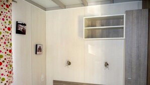 A bedroom with a bed, a wardrobe, and a shelf unit. - 4/6-person CLIMATIZED WOODEN CHALET, near Algajola beach, countryside & village views (Pigna)