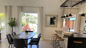 Una cocina moderna con comedor, que incluye una isla grande con taburetes, una planta en maceta y vistas al exterior.
