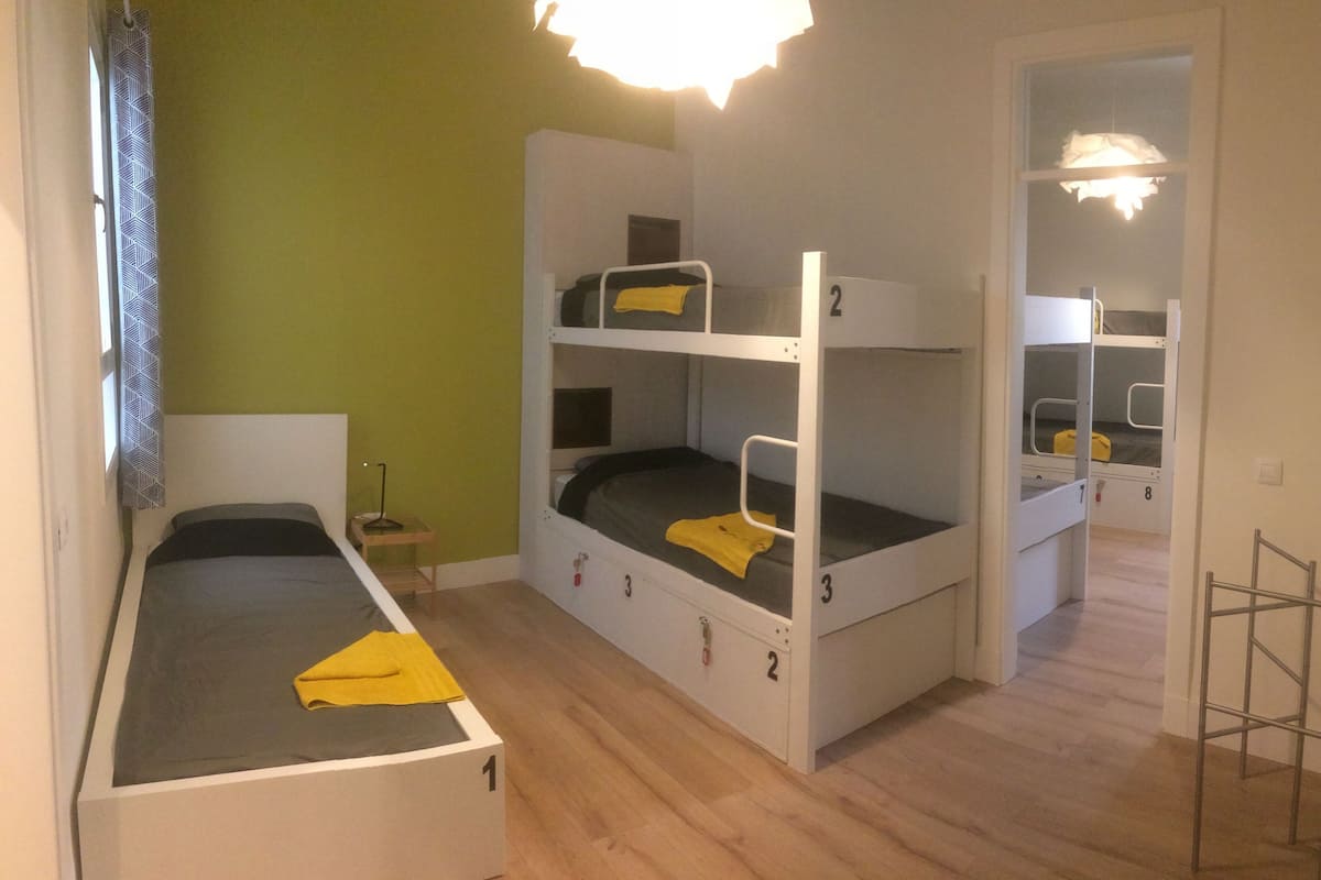 A dormitory room with bunk beds, a desk, and a chair.