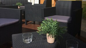 Un espacio al aire libre con mobiliario de mimbre y una planta en maceta.