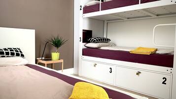 Een slaapkamer met een stapelbed, een eenpersoonsbed en een bureau met een plant.