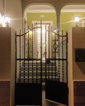 A gated entrance with a staircase leading to a room with a chandelier. - Hostel Gran Canaria (Las Palmas de Gran Canaria)