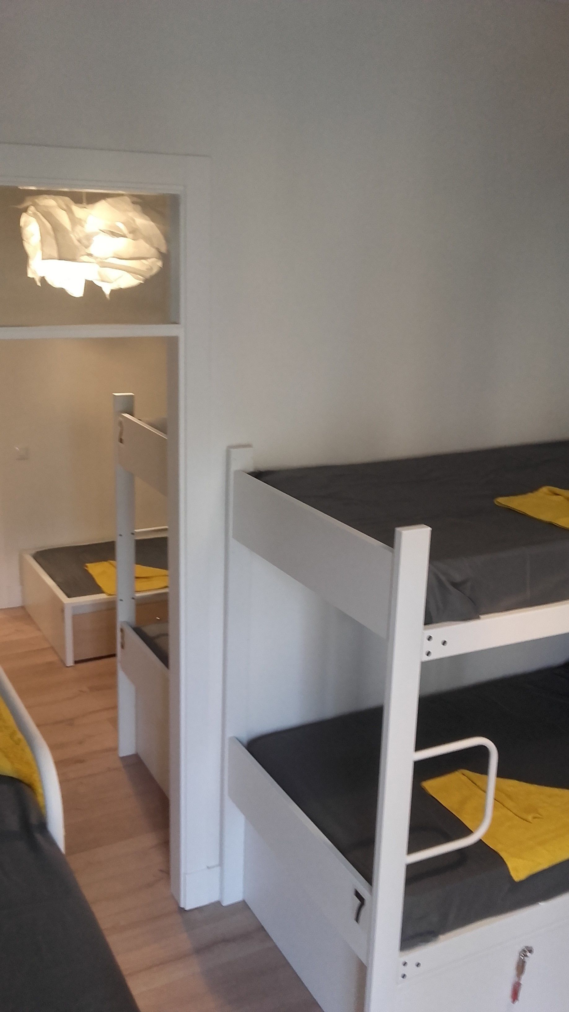 Habitación con literas, un armario pequeño y una lámpara colgante.