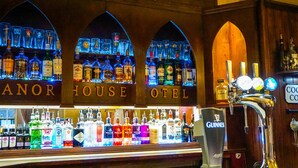 A bar area with multiple liquor bottles and a tap labeled "COCKTAIL CORNER". - Manor House Hotel Cockermouth (Cockermouth)