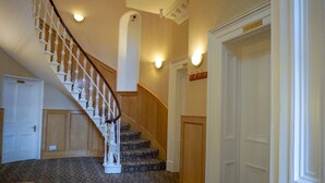 A staircase with a wooden handrail and carpeted steps, leading to a door with a sign above it. - Manor House Hotel Cockermouth (Cockermouth)
