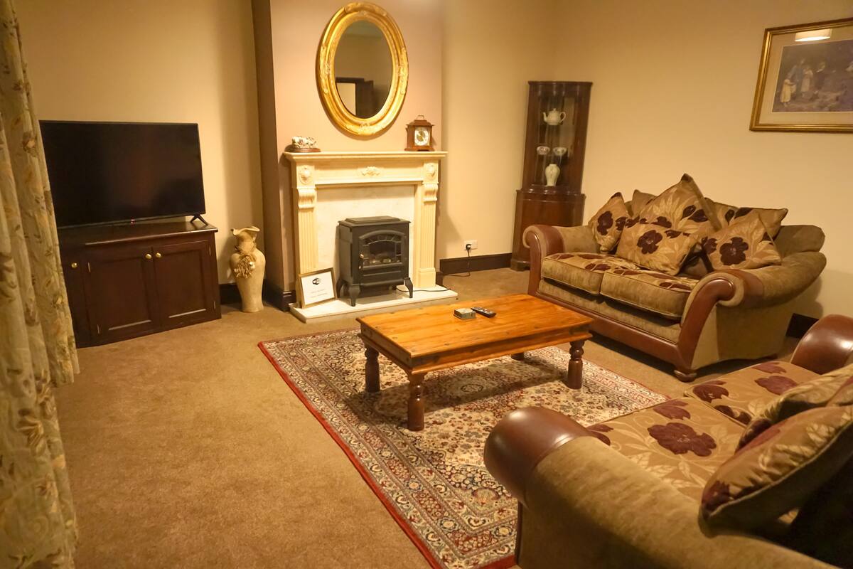 A living room with a fireplace, sofa, coffee table, and television.