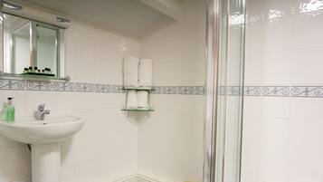 A bathroom with a sink, mirror, and shower area.
