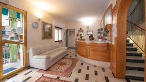 Una sala de estar con un sofá, un mostrador de recepción de madera, un tapete estampado y una escalera.