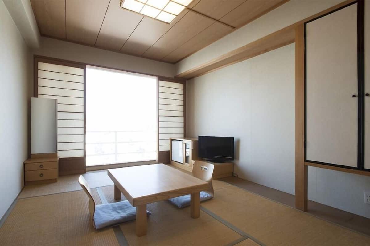 Een traditionele Japanse kamer met tatami vloeren, een lage tafel, een televisie en schuifdeuren.