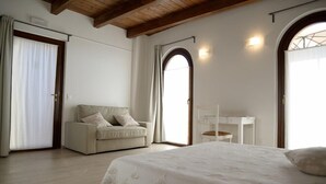 Un dormitorio con cama, sofá, escritorio y ventana con cortinas.