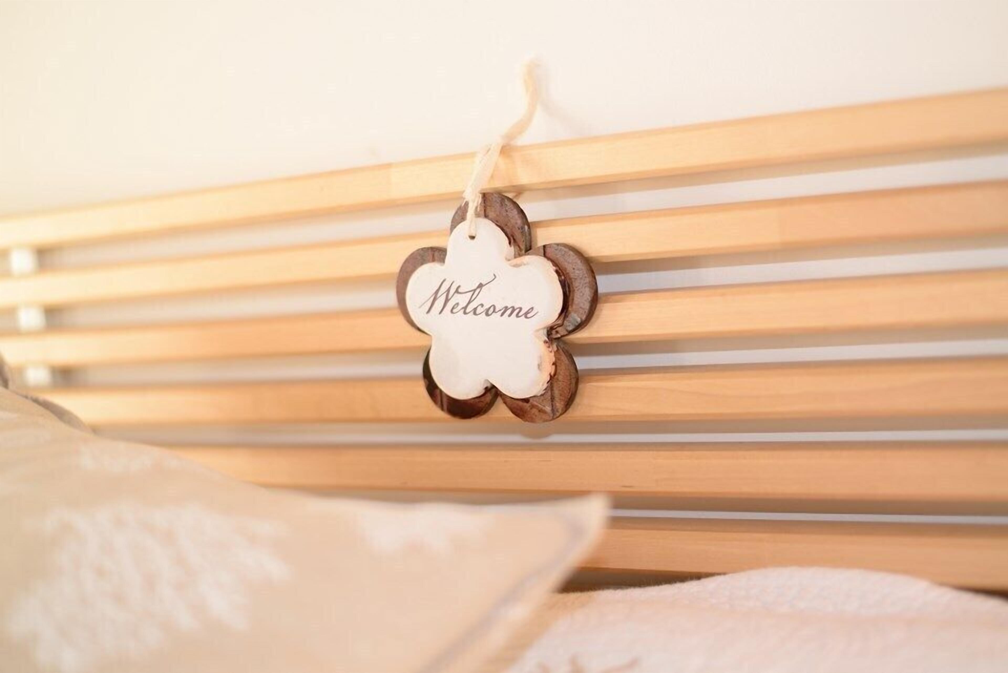 Un cabecero de madera con listones horizontales y un cartel que dice 'Welcome' colgado.