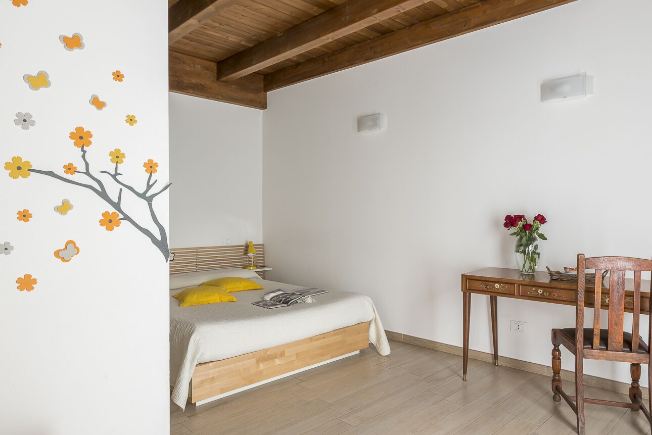 A bedroom with a bed, a desk, and a chair.