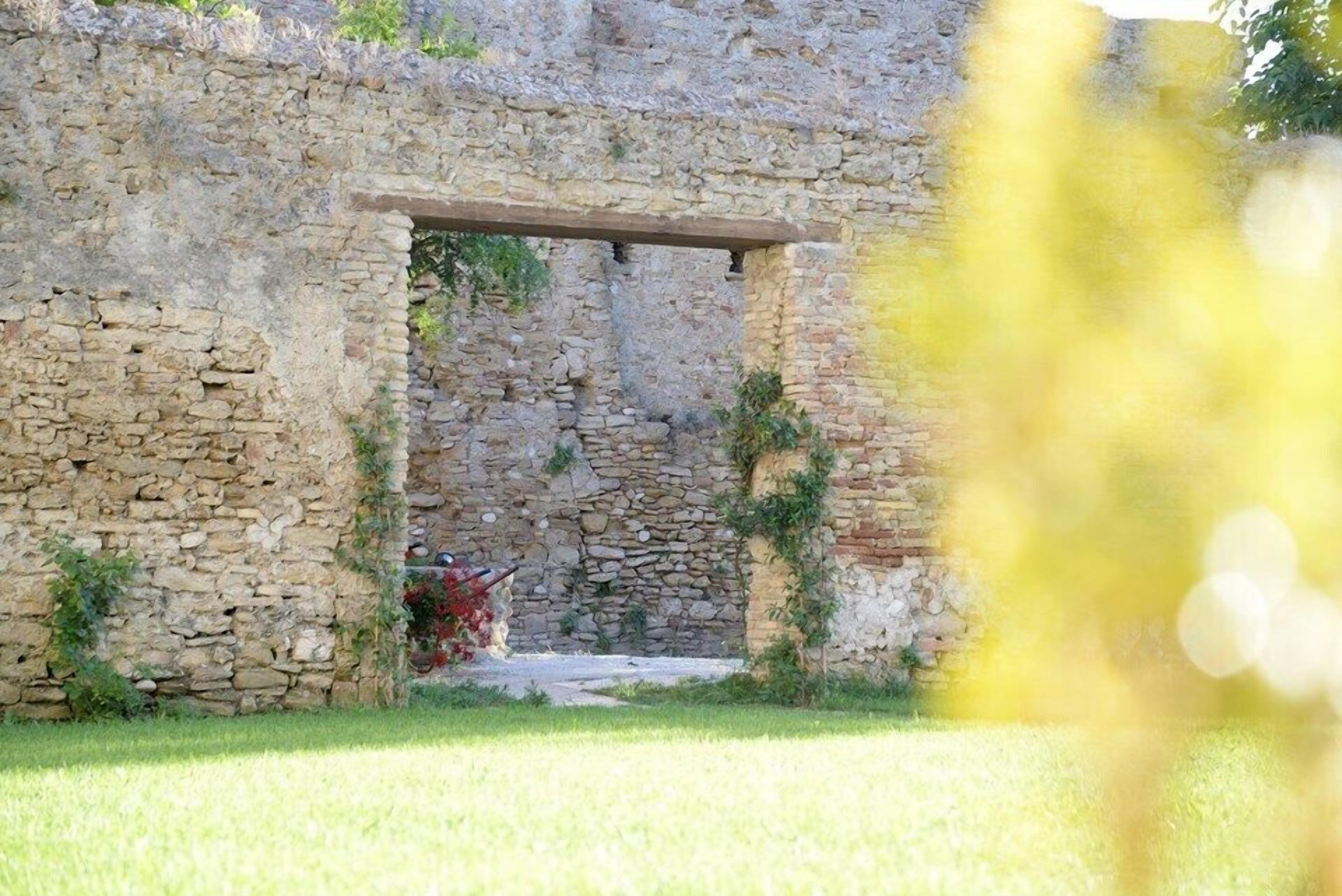 A stone archway leading into a building with a grassy foreground.