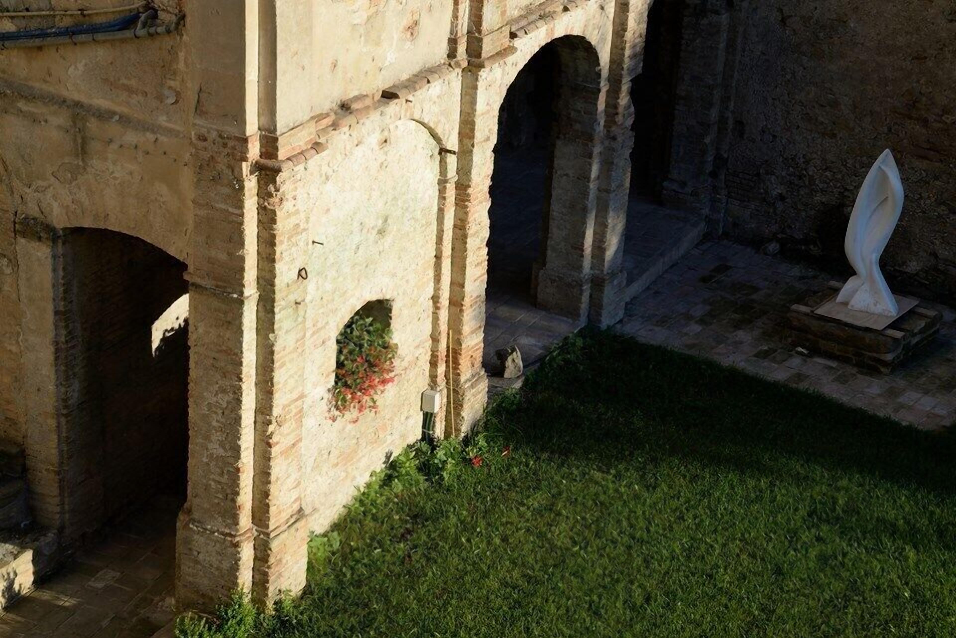 An ancient stone structure with arches and a grassy area.