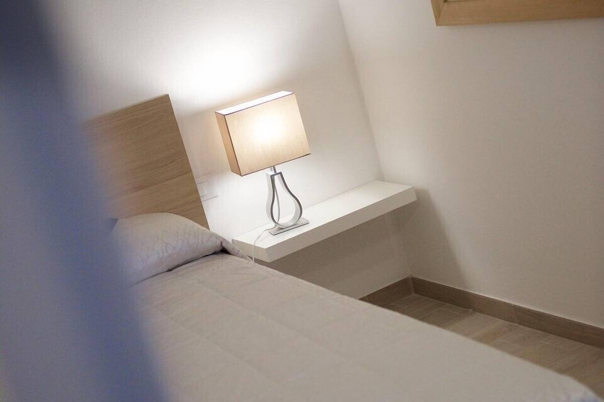 Une chambre d’hôtel avec un lit, une table de chevet avec une lampe et un tableau au mur.