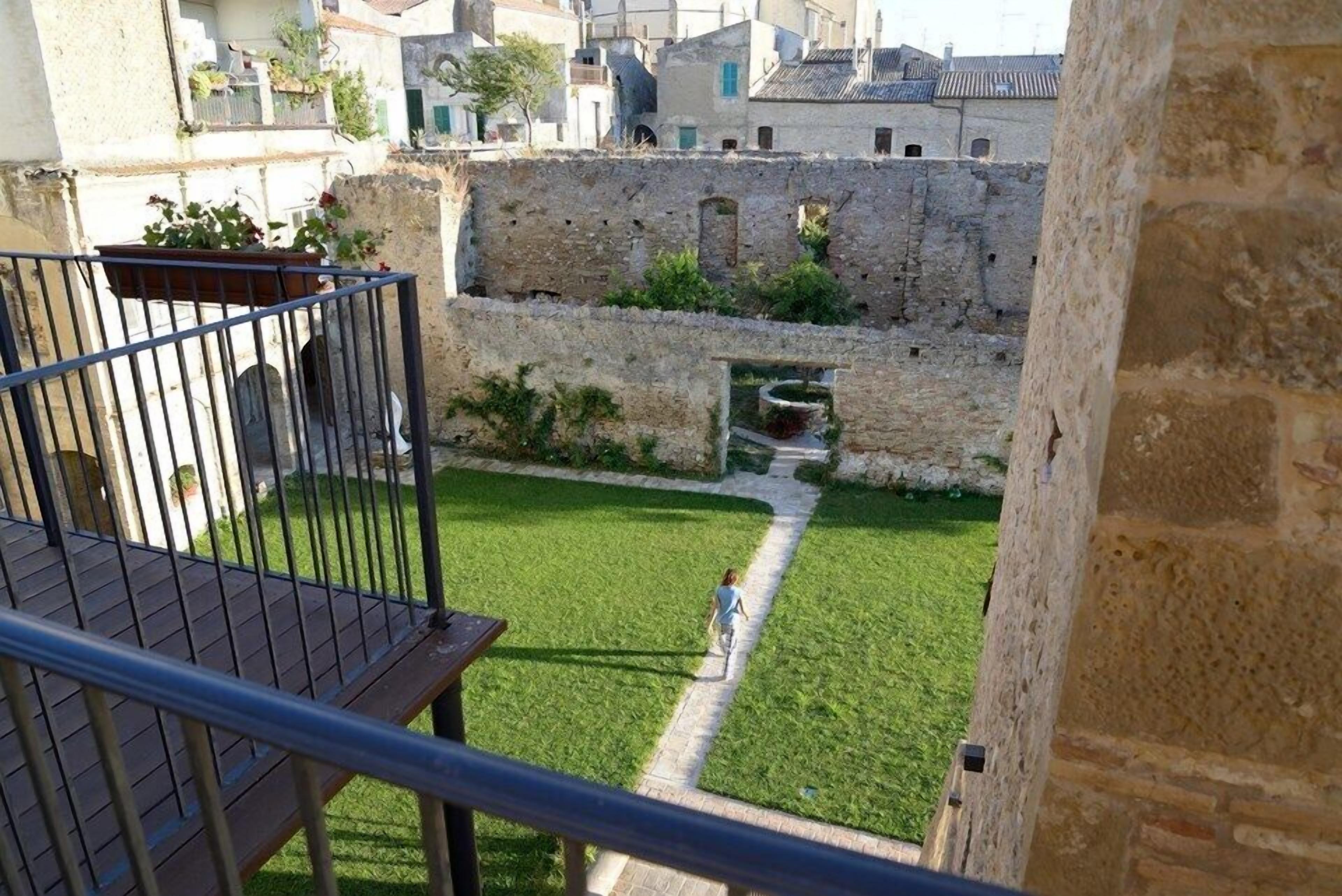 Un patio con césped, un muro de piedra y un sendero.