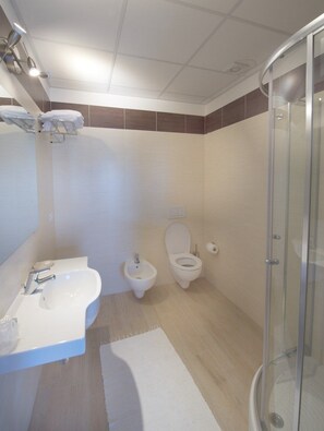 A modern bathroom with a glass shower enclosure, a sink, and two toilets. - Torre della Loggia - Dimora Storica (Ortona)