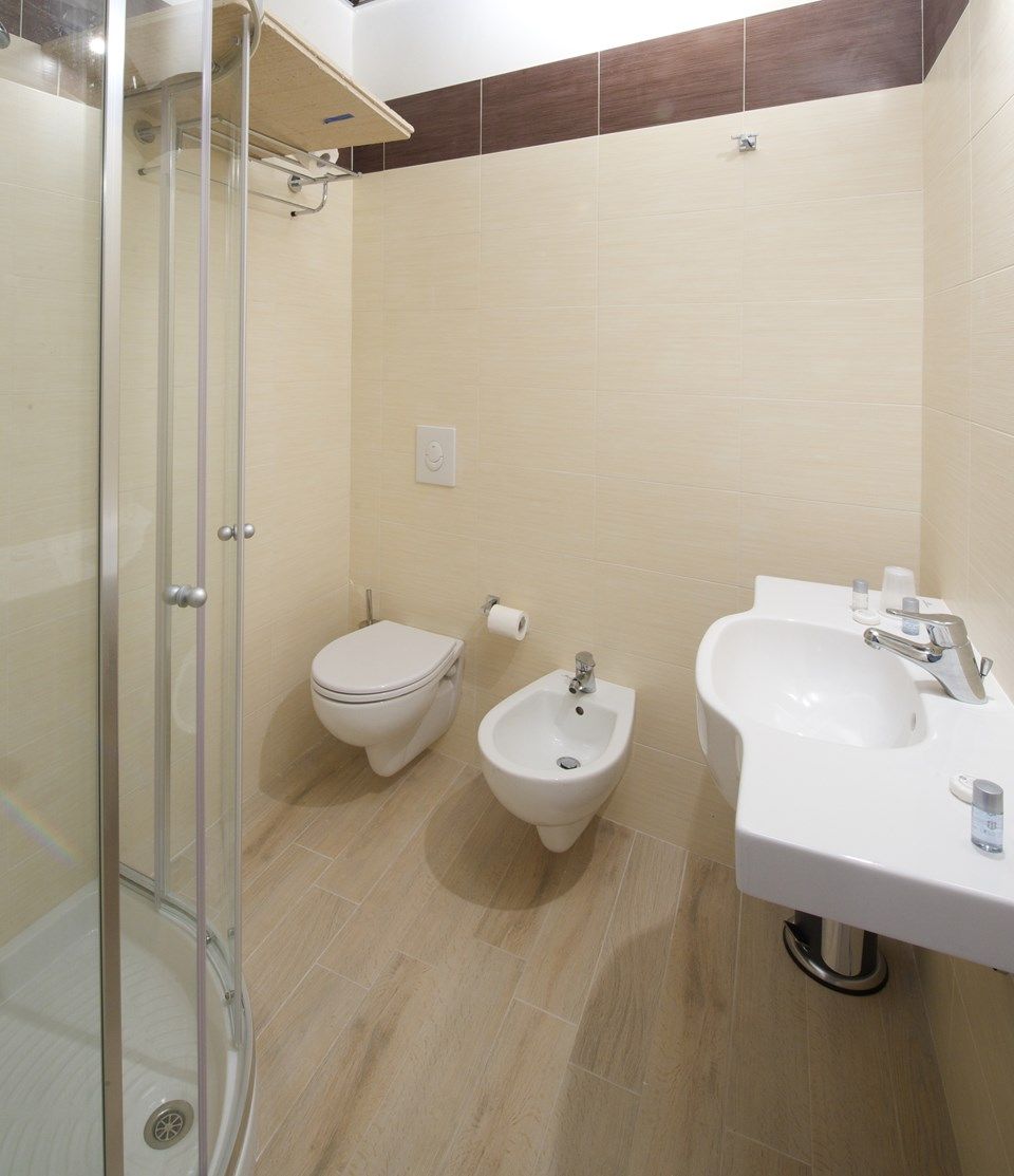 A bathroom with a glass-enclosed shower, a toilet, a bidet, and a sink.