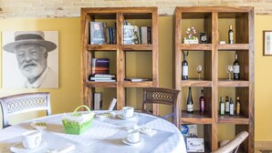 Un comedor con una mesa redonda dispuesta para dos personas, rodeado de estanterías de madera llenas de libros y botellas.