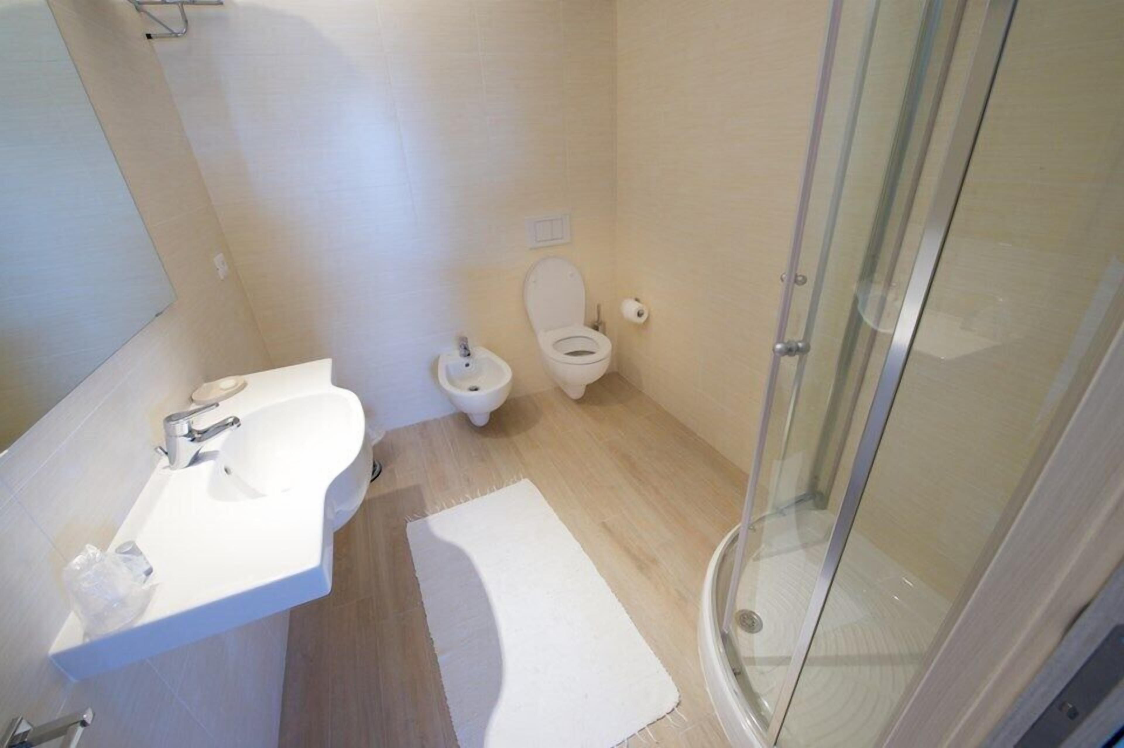 A bathroom with a white sink, toilet, and glass shower enclosure.