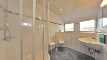 A modern bathroom with a shower, toilet, and sink.