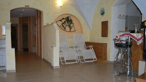 Ein Zimmer mit hohen Decken, einer Bar mit Sitzgelegenheiten und einer Sitzecke mit Stühlen.