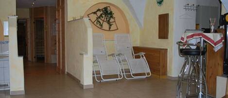 Una habitación con techo alto, una zona de bar con taburetes y un espacio de estar con sillas.