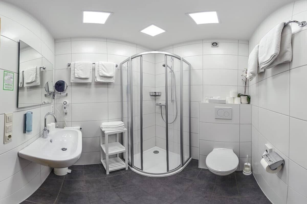 Et moderne badeværelse med bruseniche, vask, toilet og spejl.