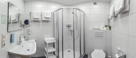 A modern bathroom with a glass-enclosed shower, a sink, a toilet, and a mirror.