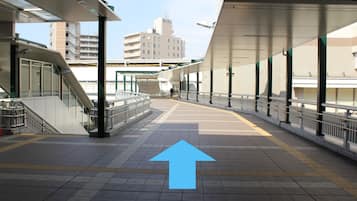 A train station platform with a directional arrow, a staircase, and a building in the background.