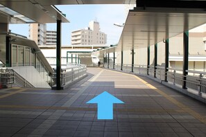 A train station platform with a directional arrow, a staircase, and a building in the background.