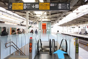Un quai de gare avec des panneaux indiquant les directions pour les sorties, les toilettes et les ascenseurs.
