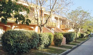 Une rangée d’immeubles résidentiels avec un escalier central, entourés de haies et d’arbres bien entretenus.